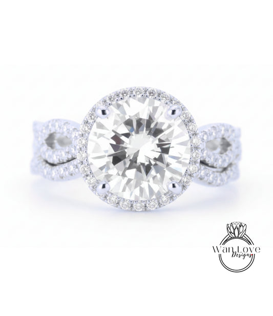 A close-up of a diamond engagement ring with a large round diamond set in a halo of smaller diamonds, surrounded by a band of smaller diamonds.