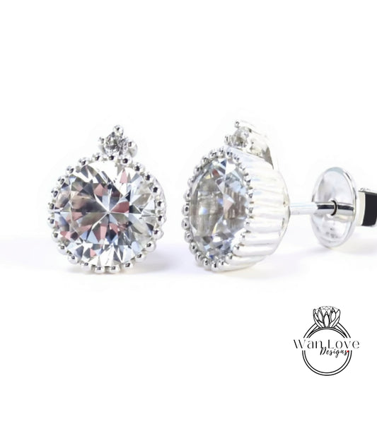 A pair of elegant diamond earrings with a large, brilliant-cut diamond set in a silver-toned metal frame.