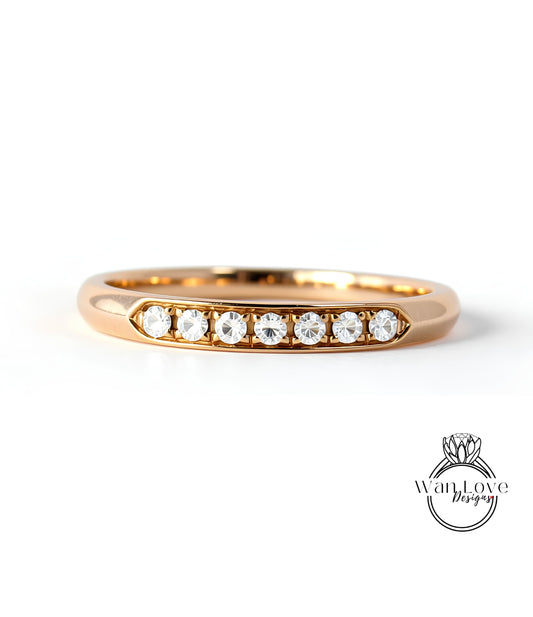 A gold ring with a row of clear gemstones set in the band.