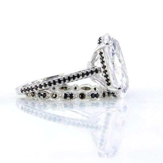 A close-up view of a diamond engagement ring with a large central diamond surrounded by smaller diamonds and a band of black and silver accents.