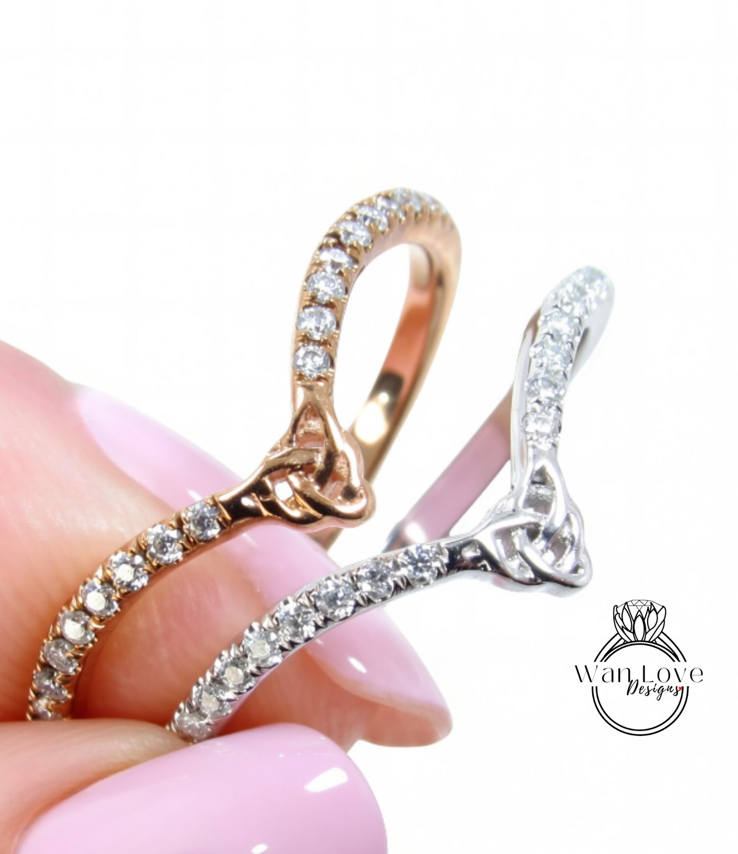 A close-up of a person's hand holding two rings with intricate designs and sparkling gemstones.