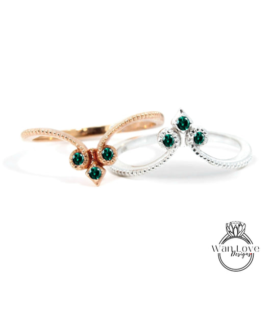 two rings with green gemstones, one silver and one gold, set against a white background.