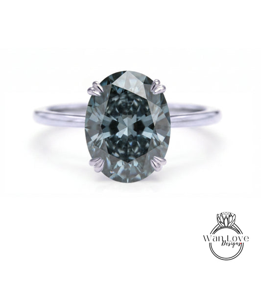 A close-up of a silver ring with a large, dark blue diamond as the centerpiece.