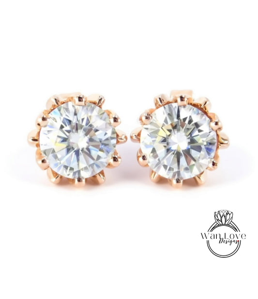 A pair of elegant gold earrings with large, clear diamonds set in a delicate, scalloped design.