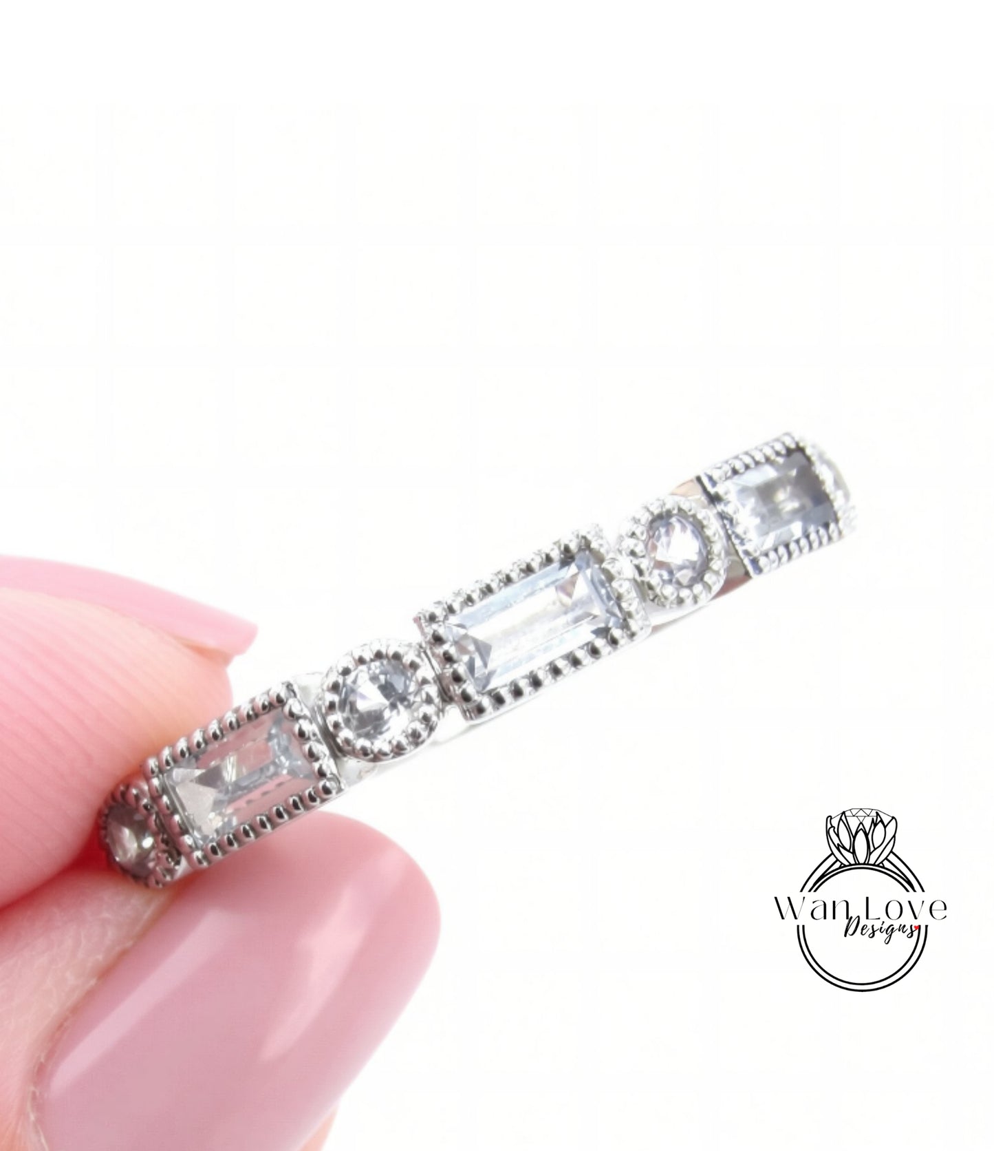 A close-up image of a person's hand holding a silver ring adorned with small, clear gemstones.