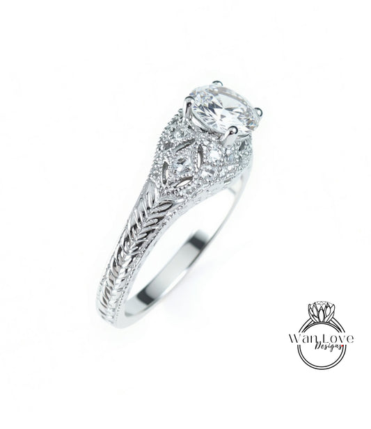 A close-up view of a silver engagement ring with a large central diamond surrounded by smaller diamonds and intricate metalwork.