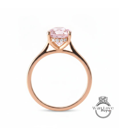 A gold ring with a pink gemstone, possibly a diamond, set in the center of the band.