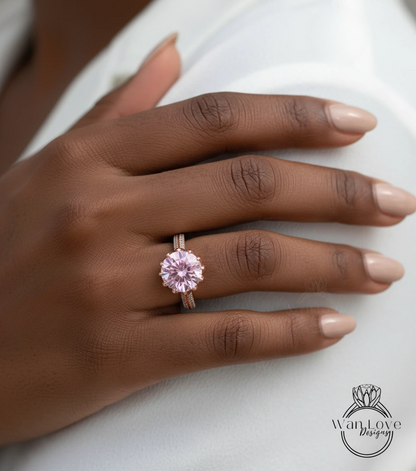 A close-up of a person's hand wearing a pink diamond engagement ring.