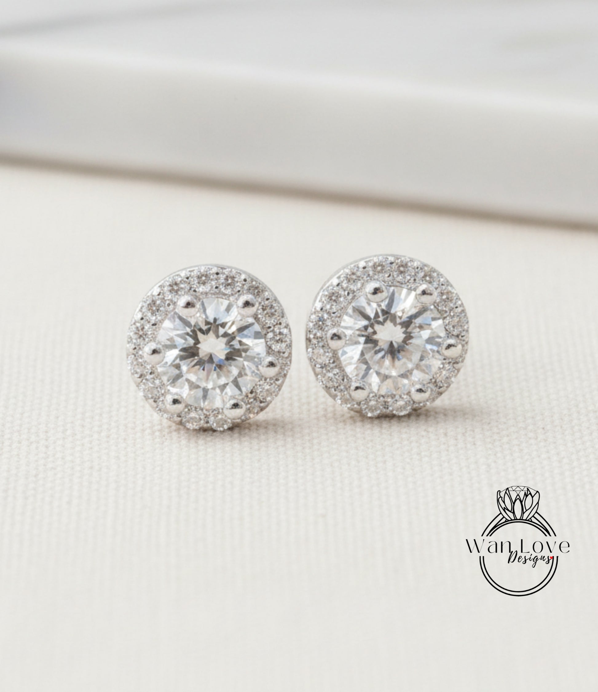 A pair of elegant diamond earrings with a large central diamond surrounded by smaller diamonds, resting on a white surface.