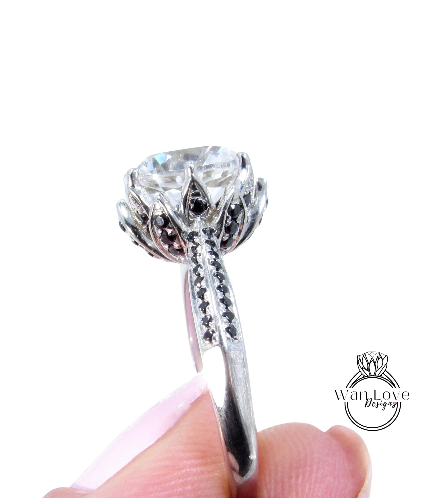 A close-up of a person's hand holding a silver ring with a large, clear gemstone, possibly a diamond, surrounded by intricate floral designs.
