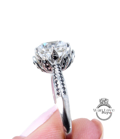 A close-up of a person's hand holding a silver ring with a large, clear gemstone, possibly a diamond, surrounded by intricate floral designs.