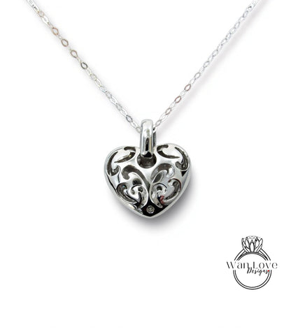A silver heart-shaped pendant with an intricate floral design on a chain.