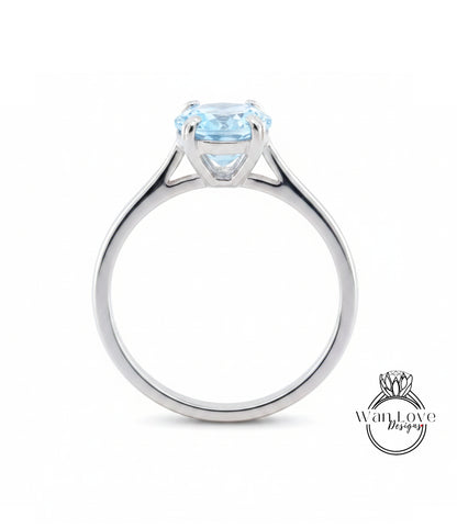 A silver engagement ring with a large blue gemstone set in the center.