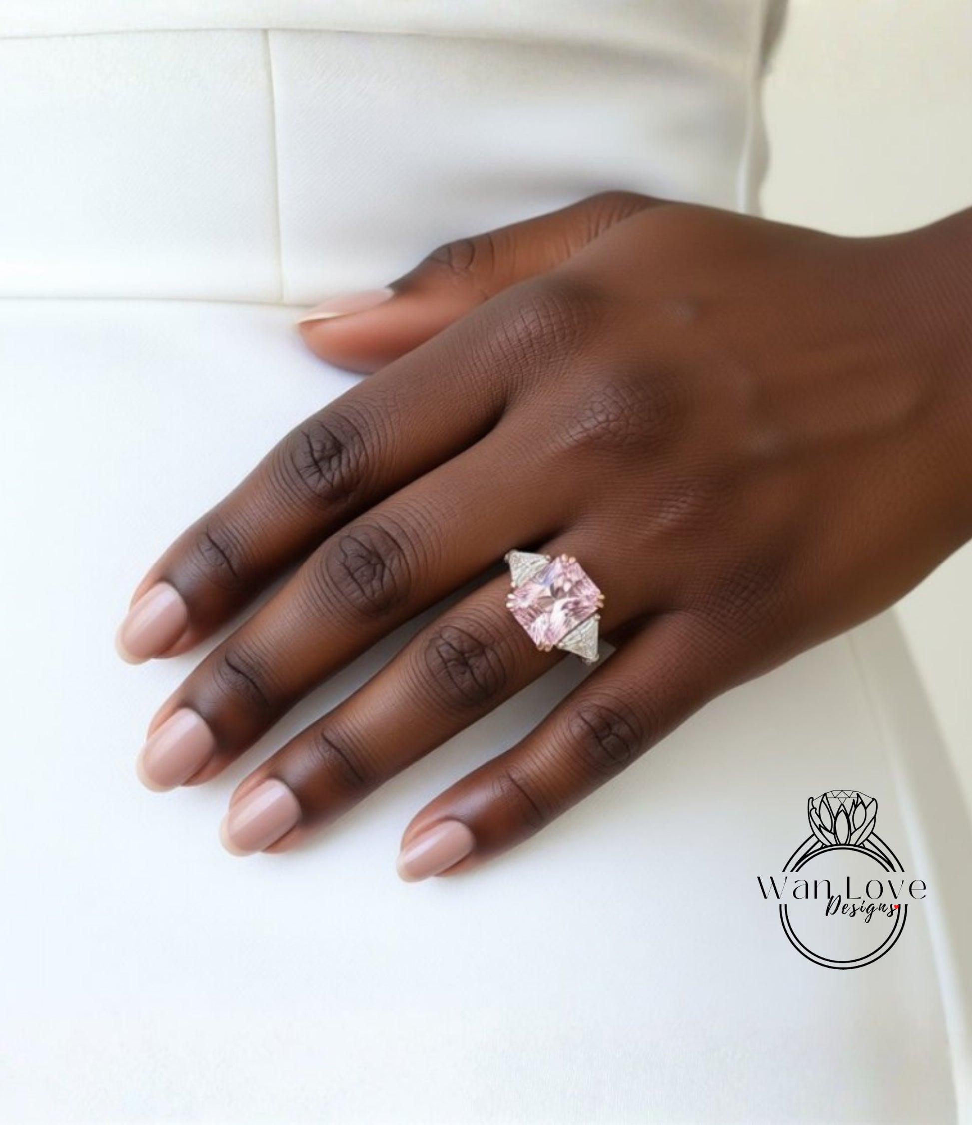 A close-up of a hand wearing a large, pink diamond ring on the ring finger.