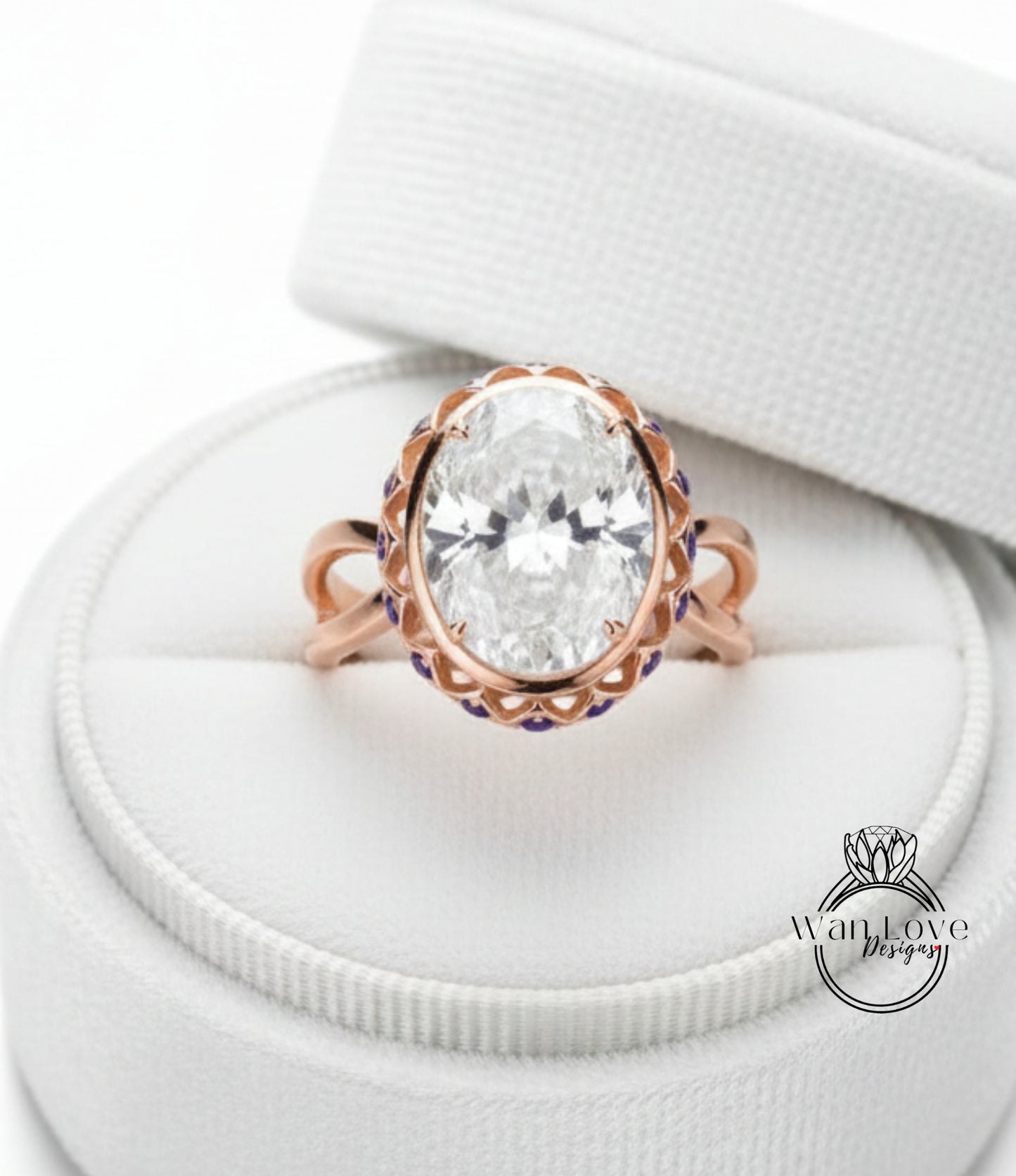 A large oval-shaped diamond ring with a scalloped edge and a large central diamond, displayed in a white jewelry box.