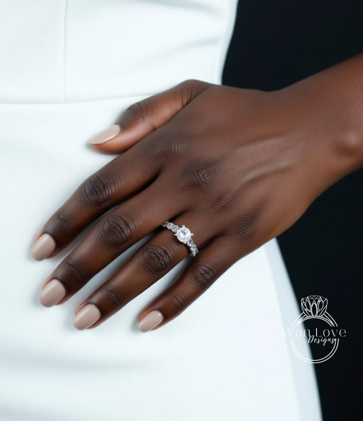 A close-up of a hand wearing a diamond engagement ring on the ring finger.