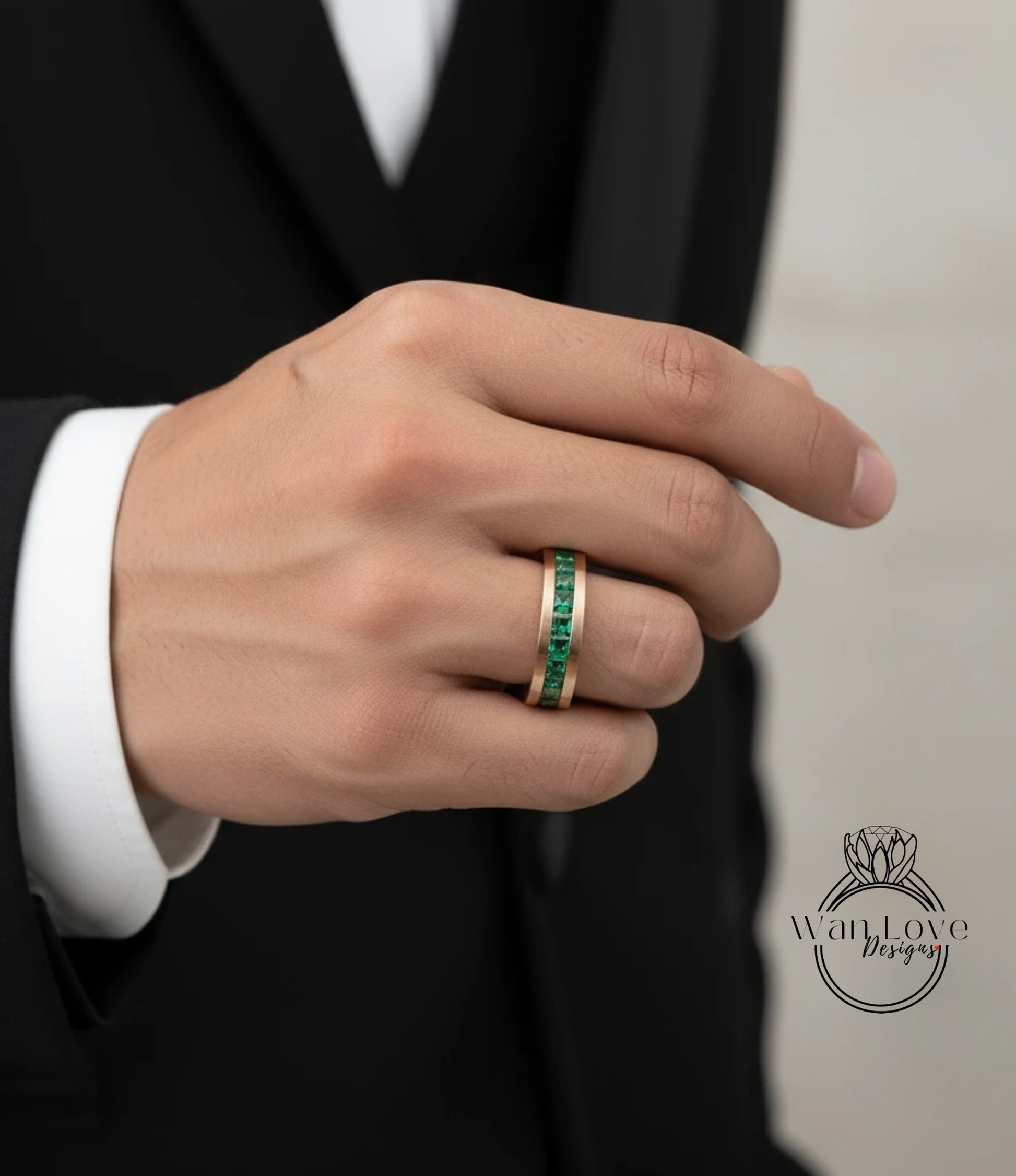 A close-up of a person's hand wearing a gold ring with green gemstones.