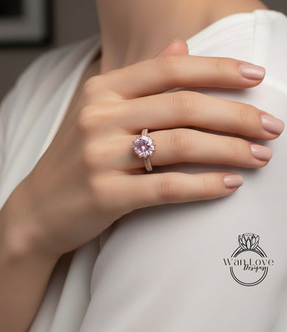 A close-up of a person's hand wearing a pink diamond ring on the ring finger.