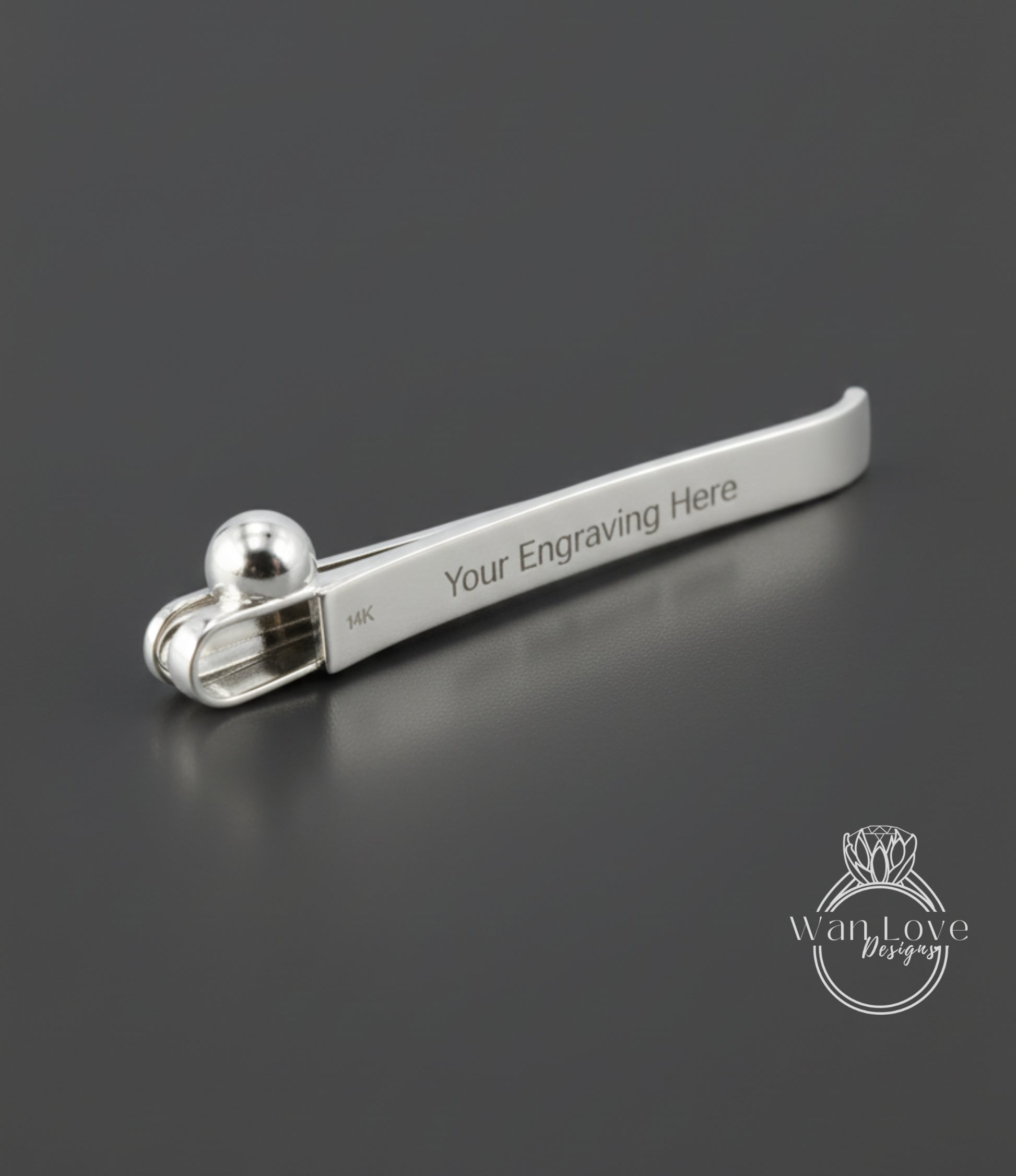 A silver-colored metal object, possibly a pen or a tool, with the text "Your Engraving Here" engraved on it.