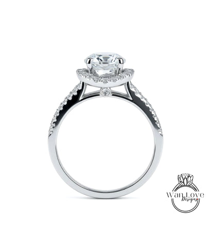 A silver engagement ring with a large central diamond and smaller diamonds on either side of the halo.