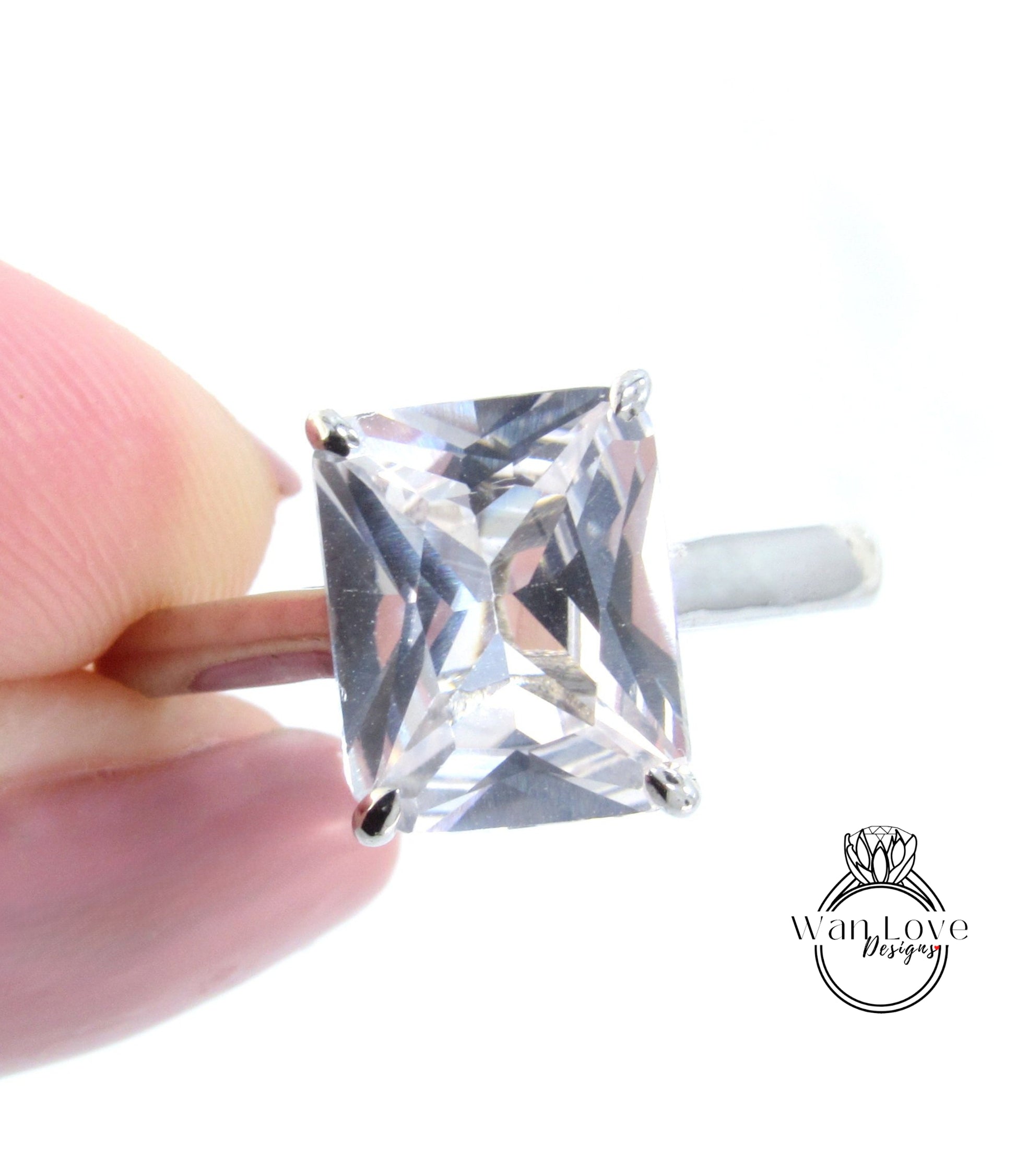 A close-up image of a person's hand holding a diamond ring with a large, clear gemstone.