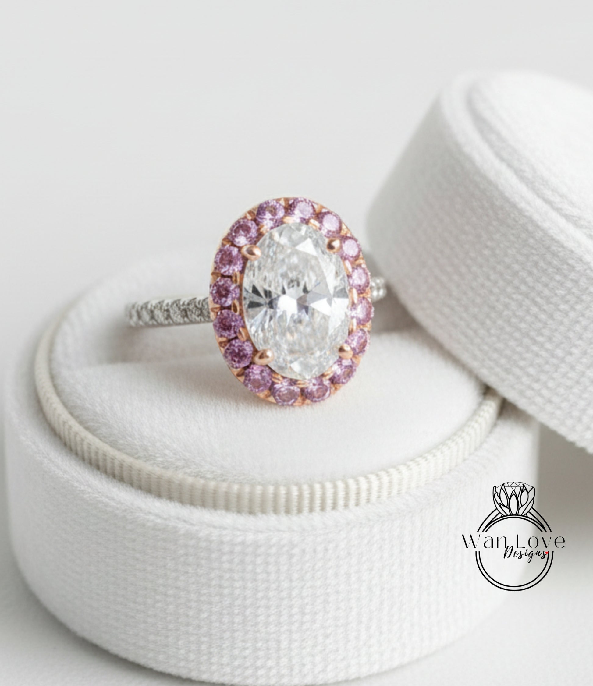A large oval-shaped diamond ring with a halo of smaller diamonds around the center, placed on a white cloth inside a white box.