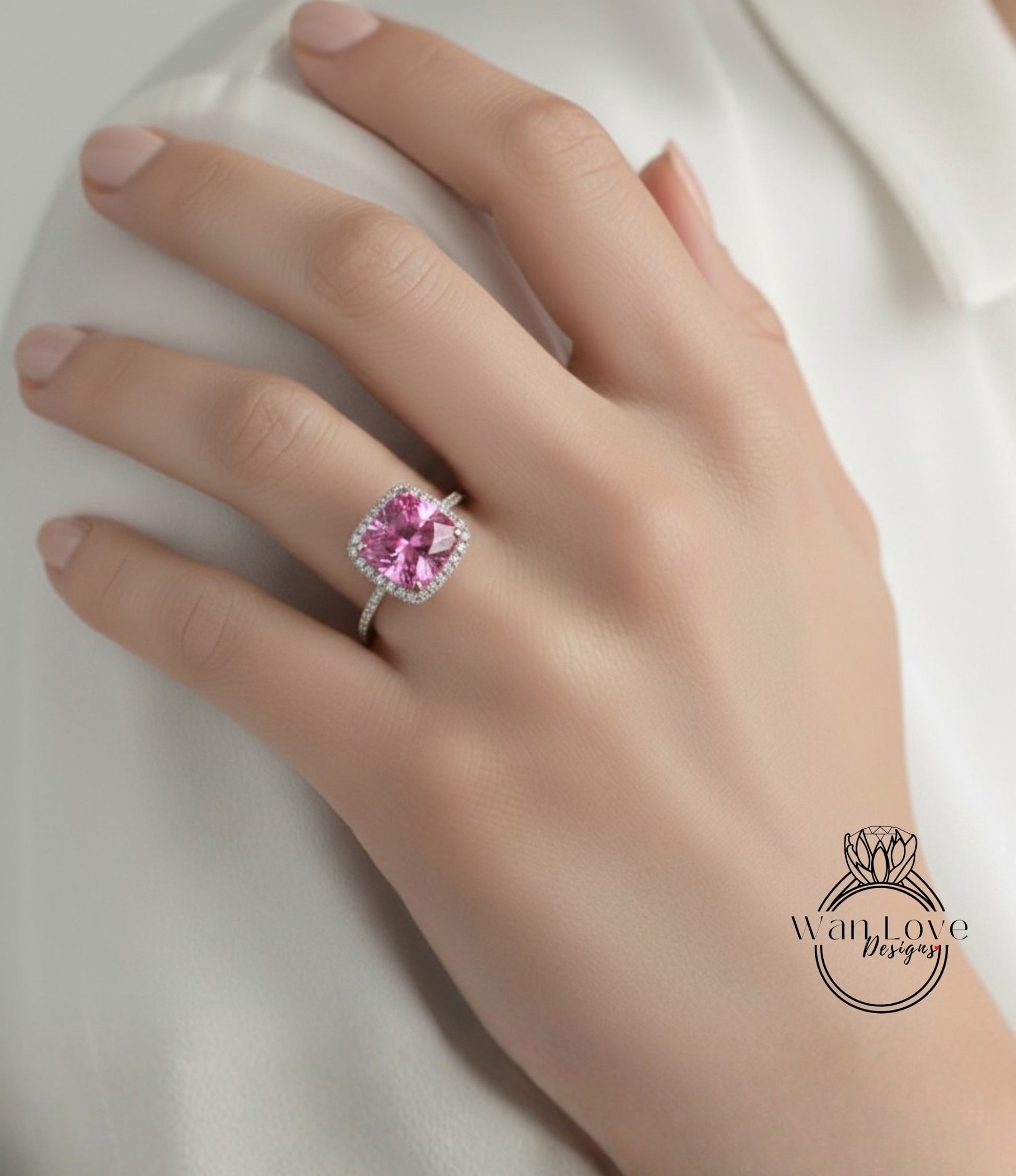 A close-up of a hand wearing a ring with a large pink gemstone, likely a diamond.