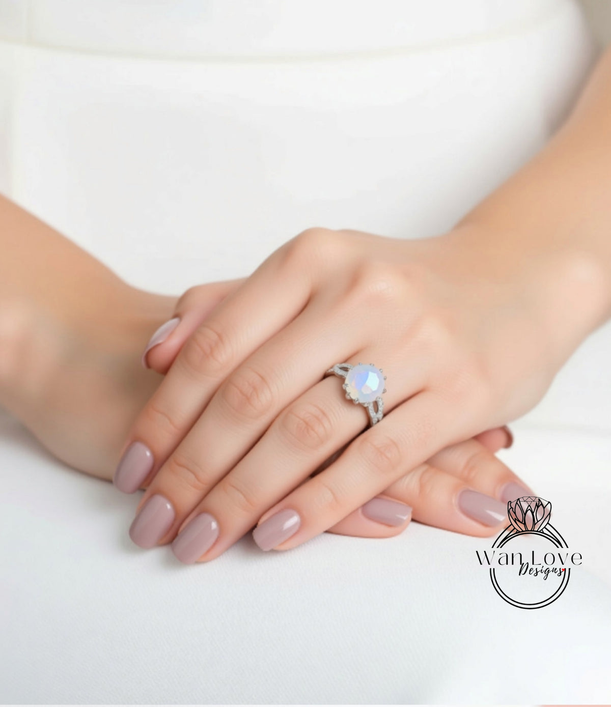 A close-up image of a person's hands with a ring on the finger, resting on a white surface.