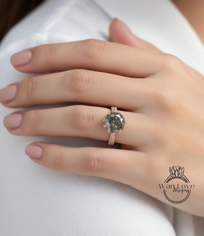 A close-up of a person's hand wearing a large, dark grey diamond ring with a pink band.