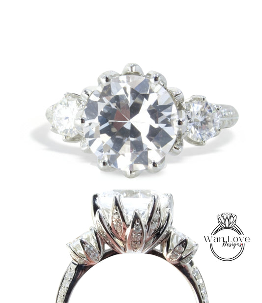 a stunning diamond engagement ring with a large central diamond surrounded by smaller diamonds on either side. The ring is set in a silver band, showcasing the intricate design and craftsmanship.