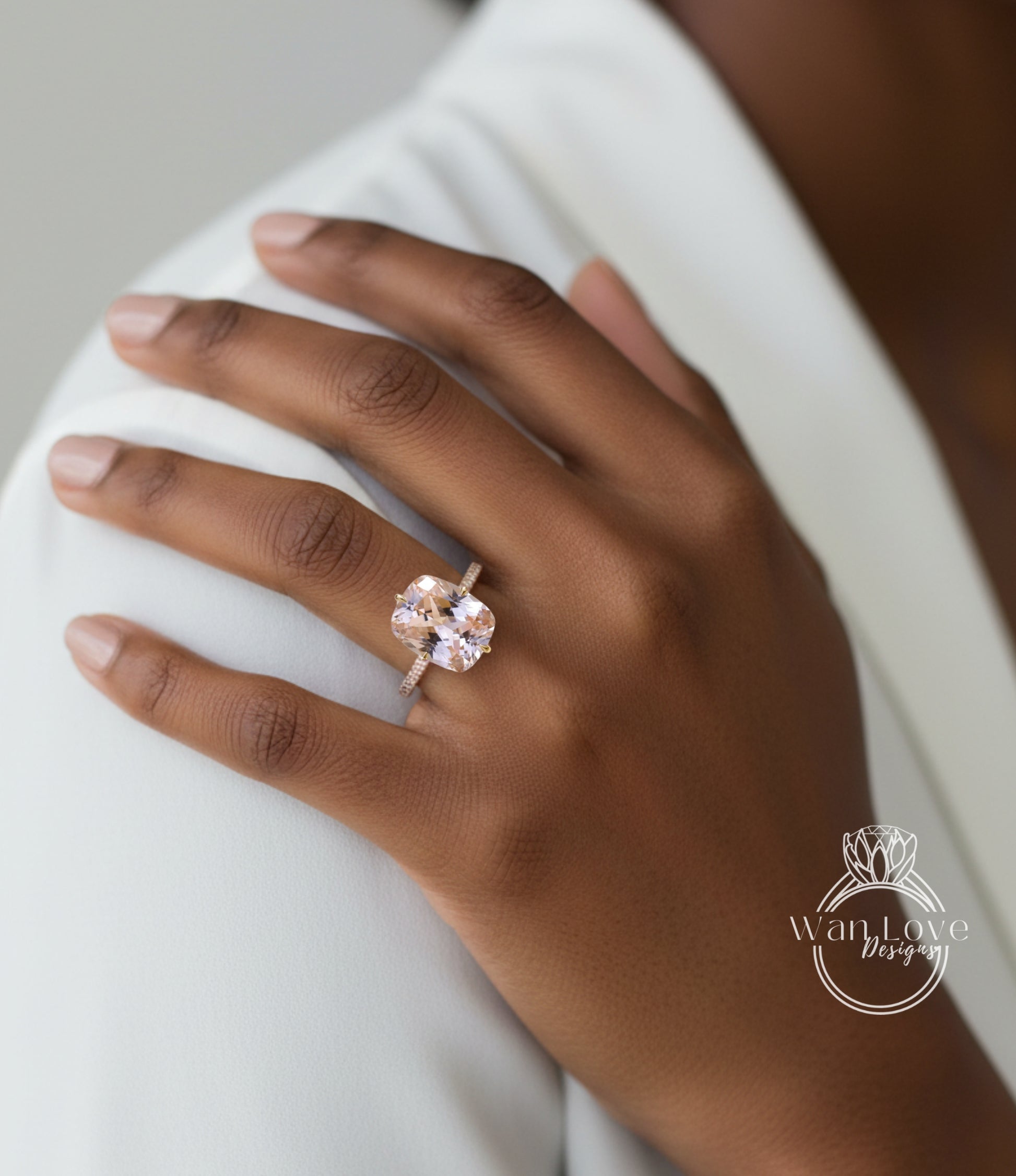 A close-up of a person's hand wearing a large, pinkish-orange gemstone ring on the ring finger.