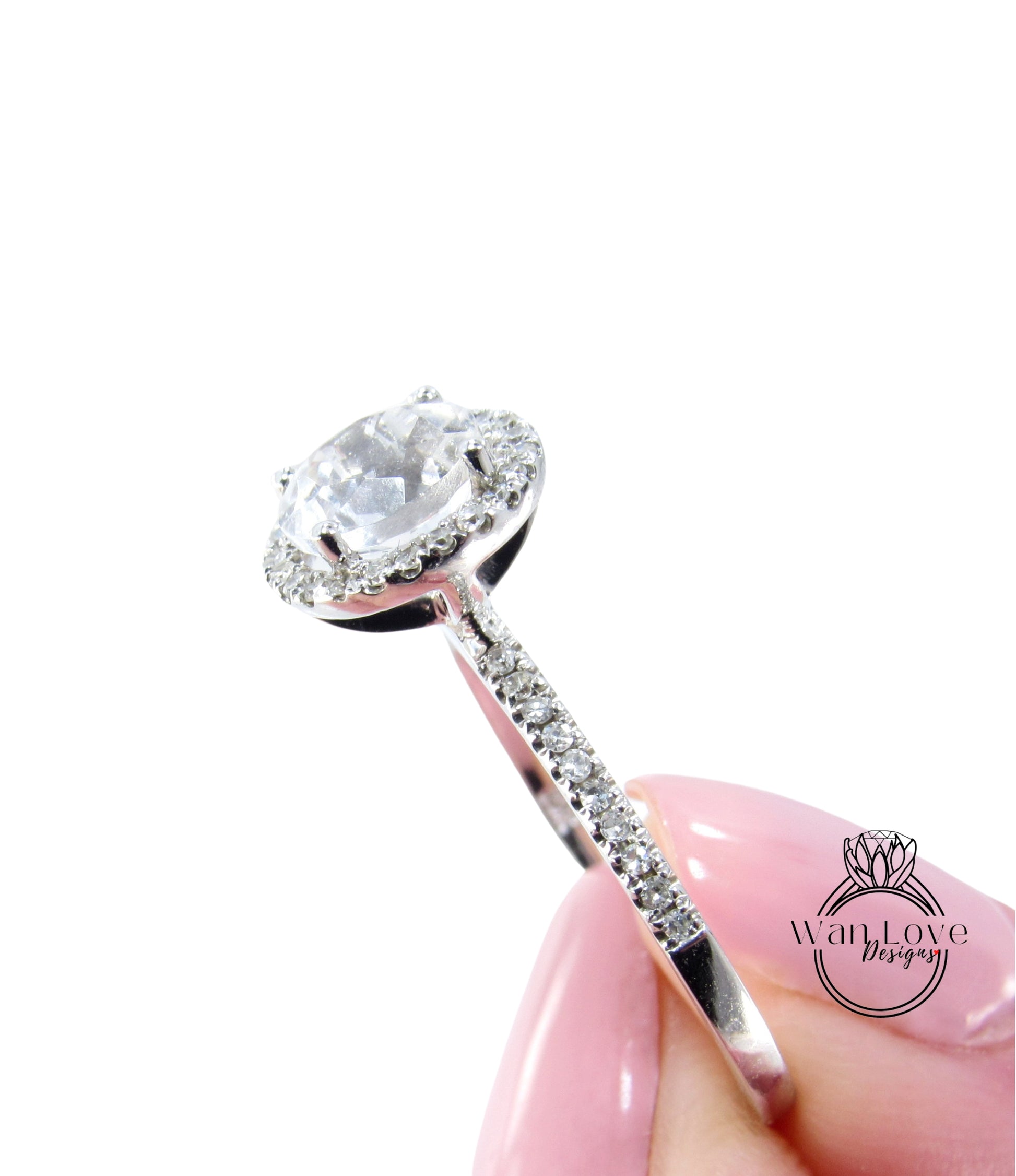 A close-up image of a person's hand holding a diamond engagement ring with a large central diamond surrounded by smaller diamonds on the band.