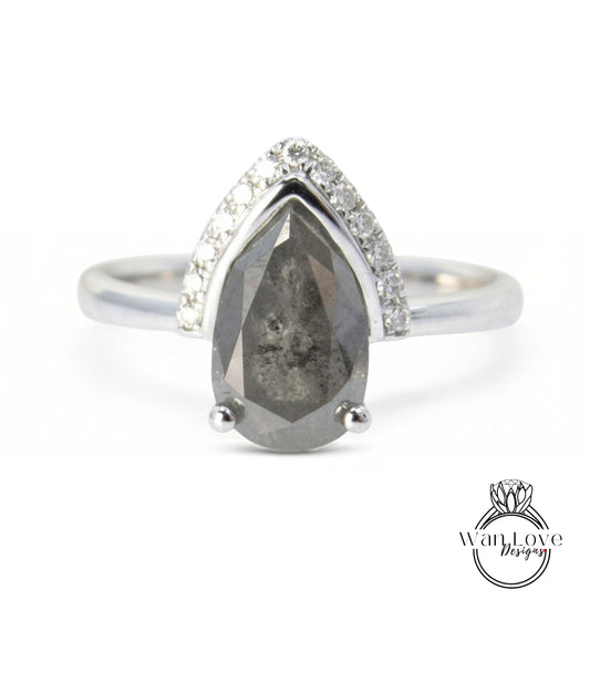 A silver ring with a large, dark grey diamond as the centerpiece, surrounded by smaller diamonds.