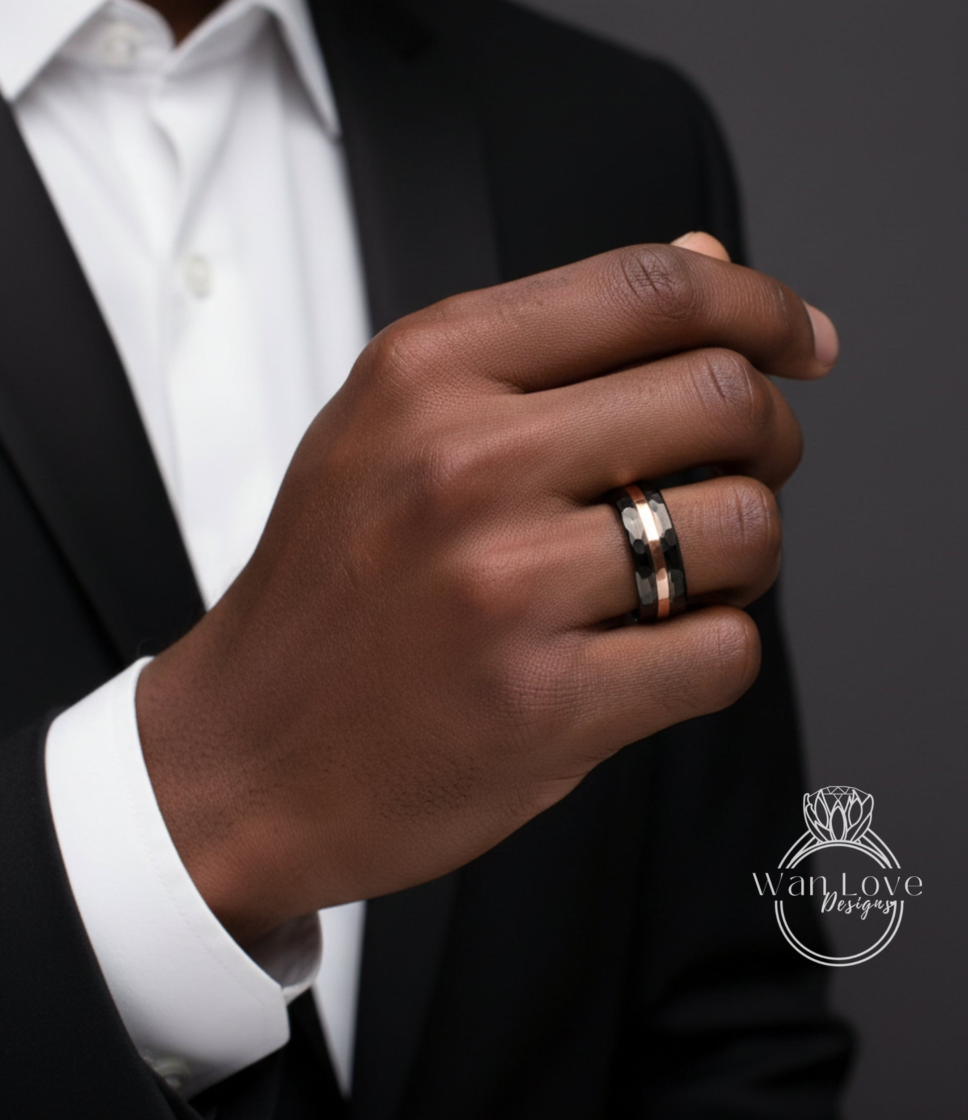 A close-up of a person's hand wearing a ring, with a black suit jacket visible.