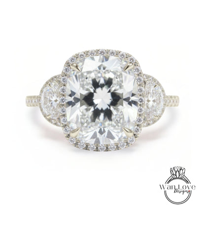 A stunning diamond engagement ring with a large central diamond surrounded by smaller diamonds on either side, set in a halo of smaller diamonds.