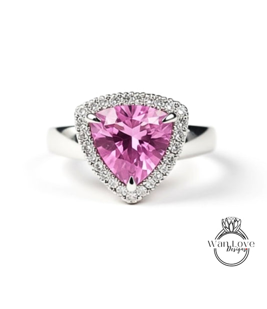 A diamond ring with a pink gemstone set in a halo of smaller diamonds.