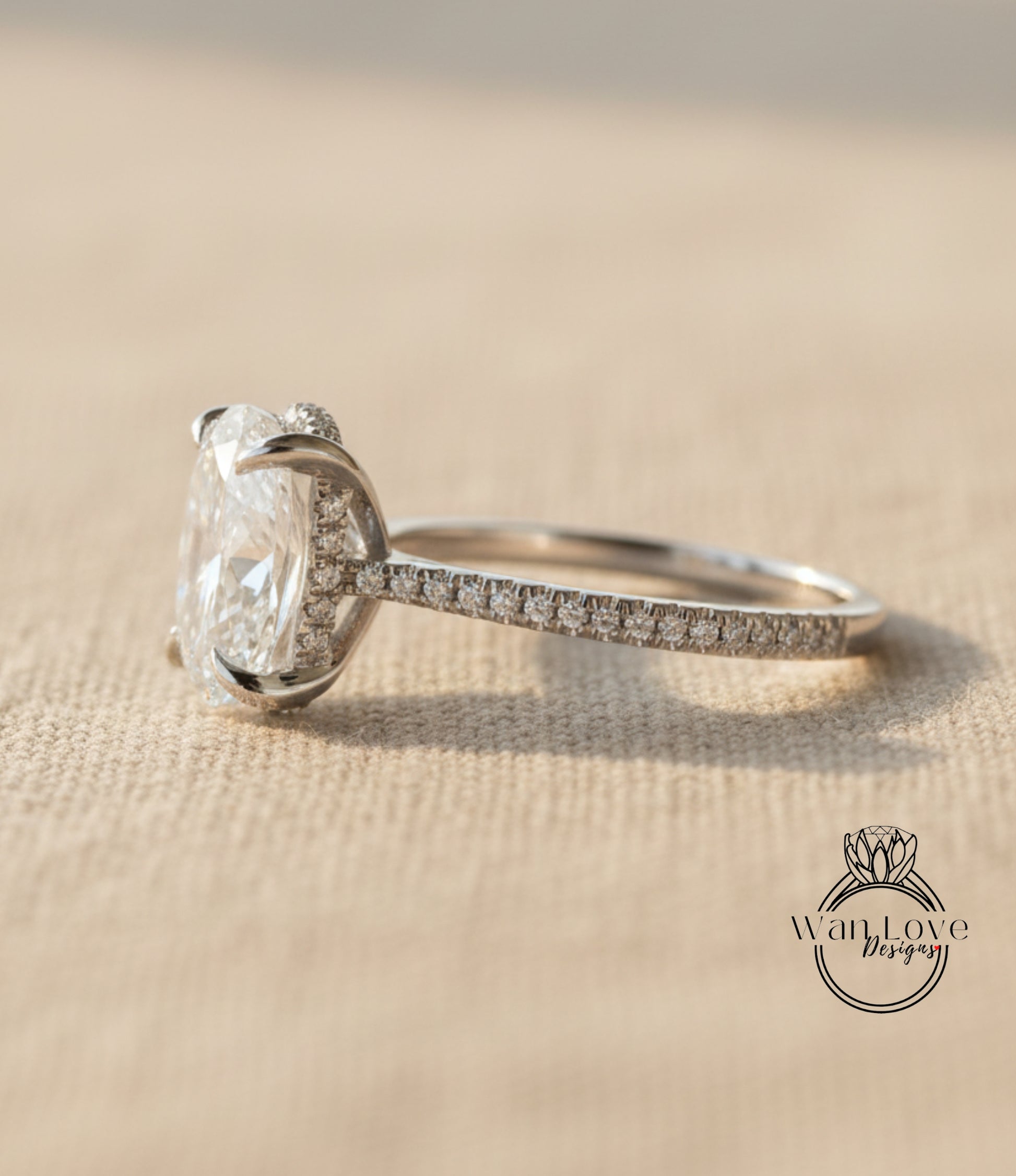 A close-up view of a diamond engagement ring with a large central diamond and smaller diamonds around the sides, resting on a textured surface.