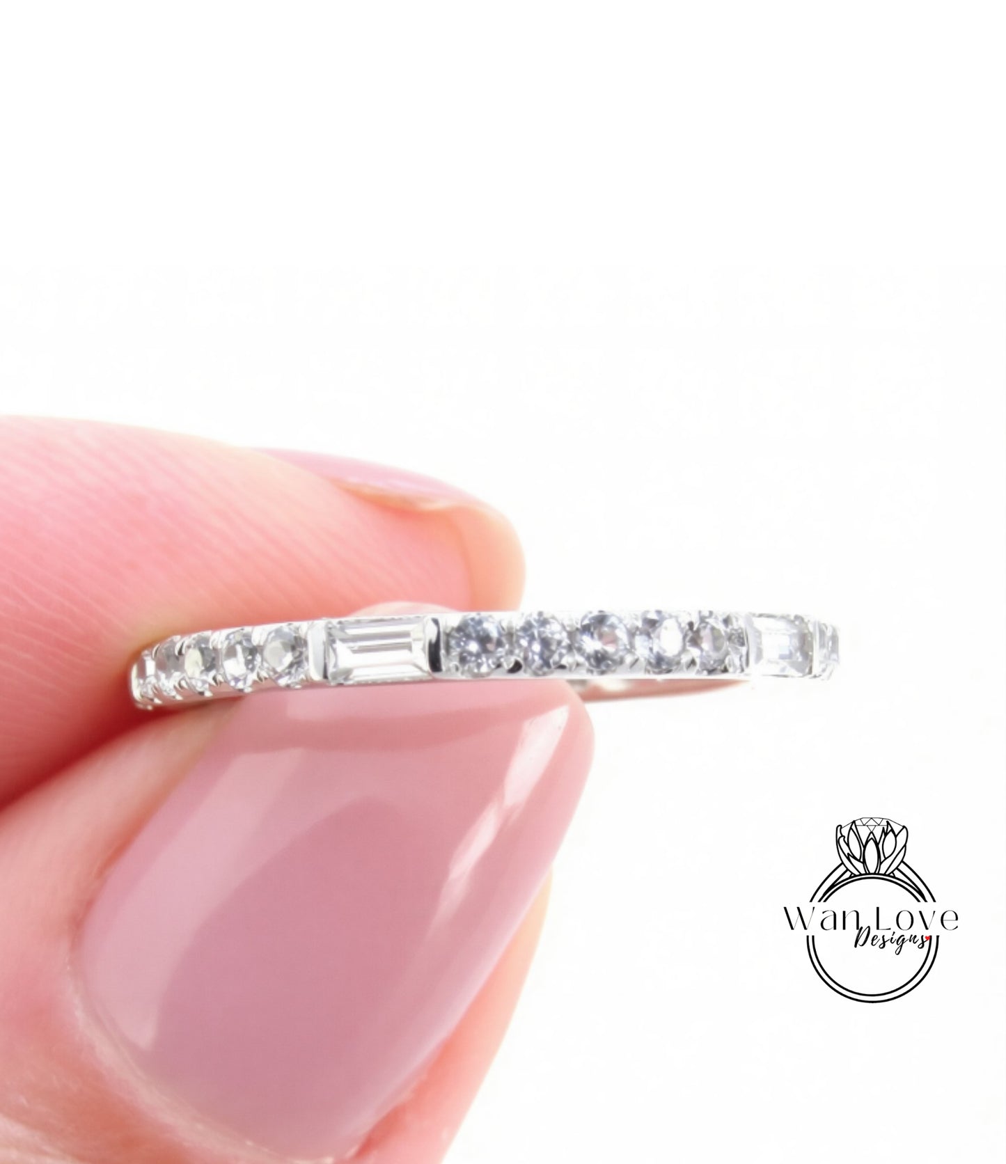 A close-up image of a person's hand holding a ring with a row of small diamonds along the band.