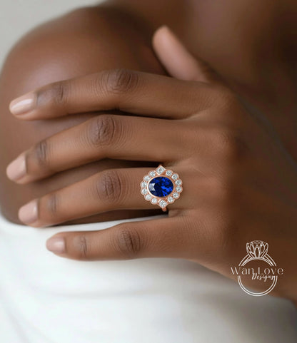 A close-up of a hand wearing a gold ring with a large blue gemstone, resting on a white surface.