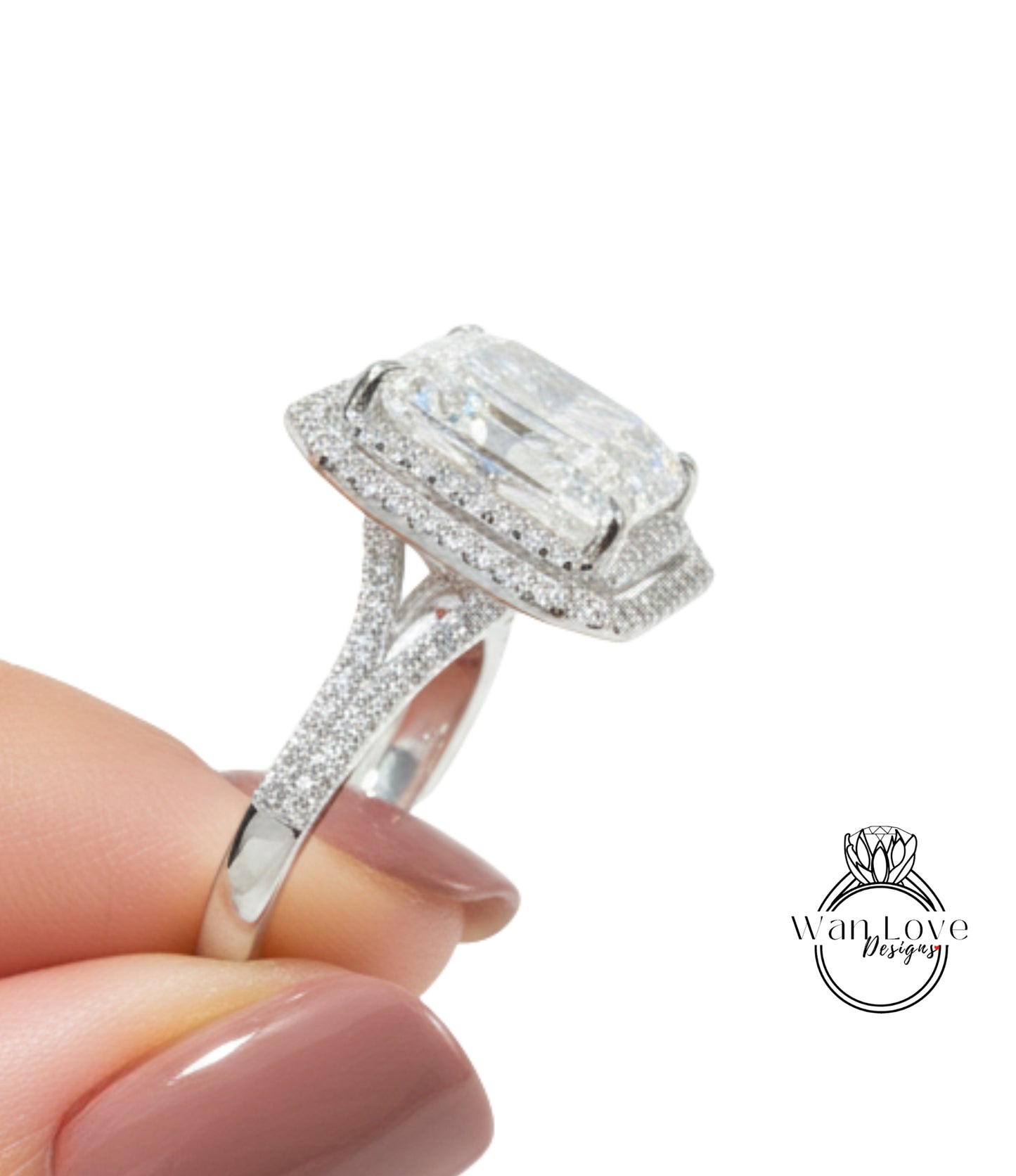 A close-up of a person's hand holding a diamond engagement ring with a large central diamond surrounded by smaller diamonds.