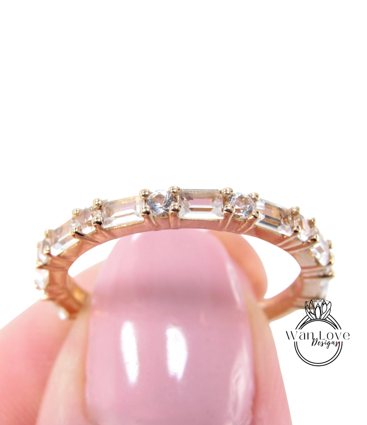 A close-up of a gold ring with a row of clear gemstones, held in a person's hand.