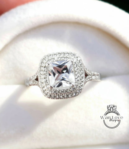 A close-up view of a diamond engagement ring with a large, clear gemstone set in a halo of smaller diamonds.