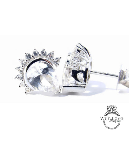 A close-up view of a pair of silver earrings with a large, clear gemstone set in the center, surrounded by smaller gemstones.