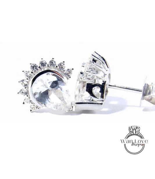 A close-up view of a pair of silver earrings with a large, clear gemstone set in the center, surrounded by smaller gemstones.