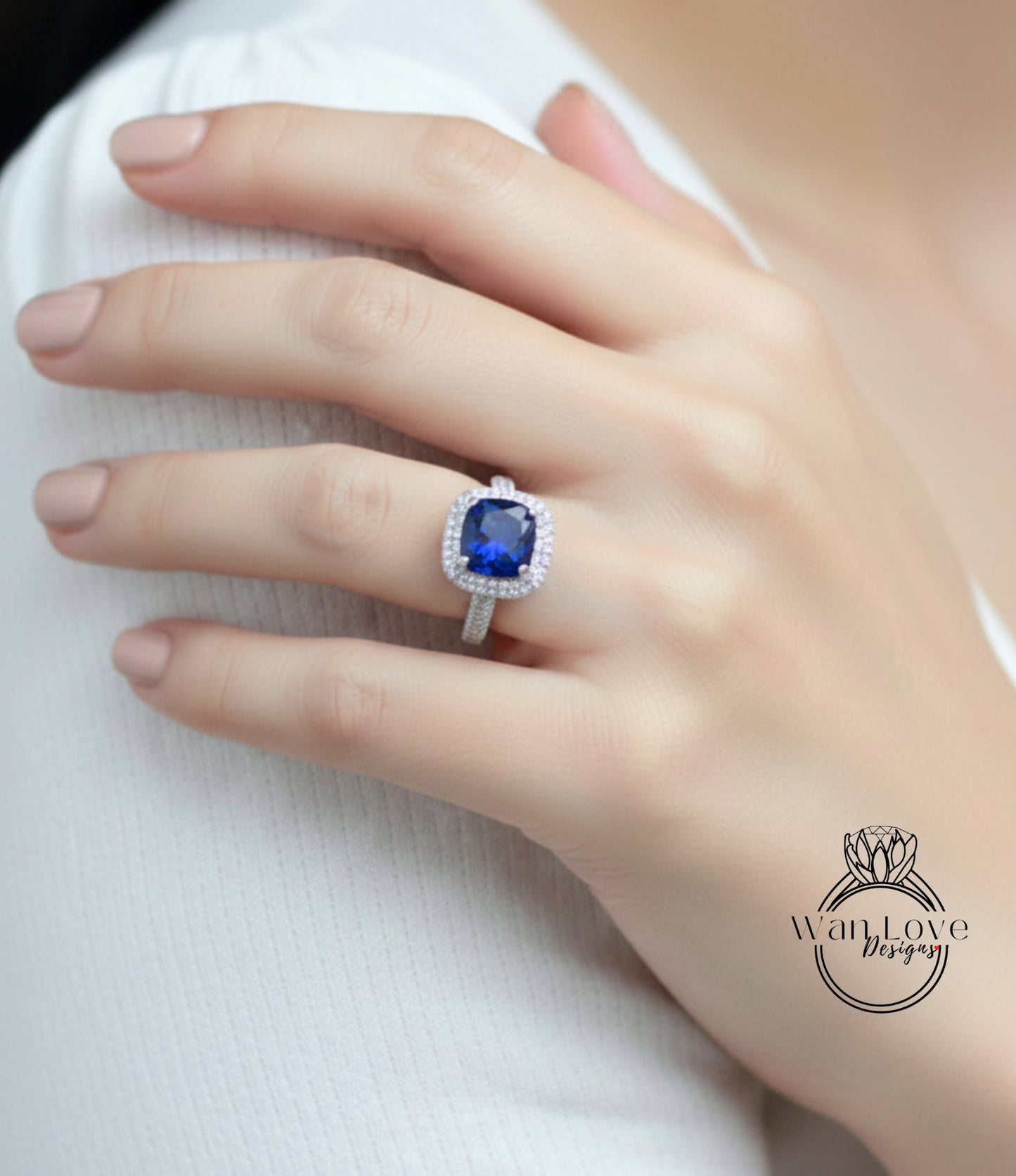 A close-up of a hand wearing a ring with a large blue gemstone, likely a sapphire, on the ring finger.