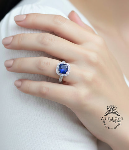 A close-up of a hand wearing a ring with a large blue gemstone, likely a sapphire, on the ring finger.