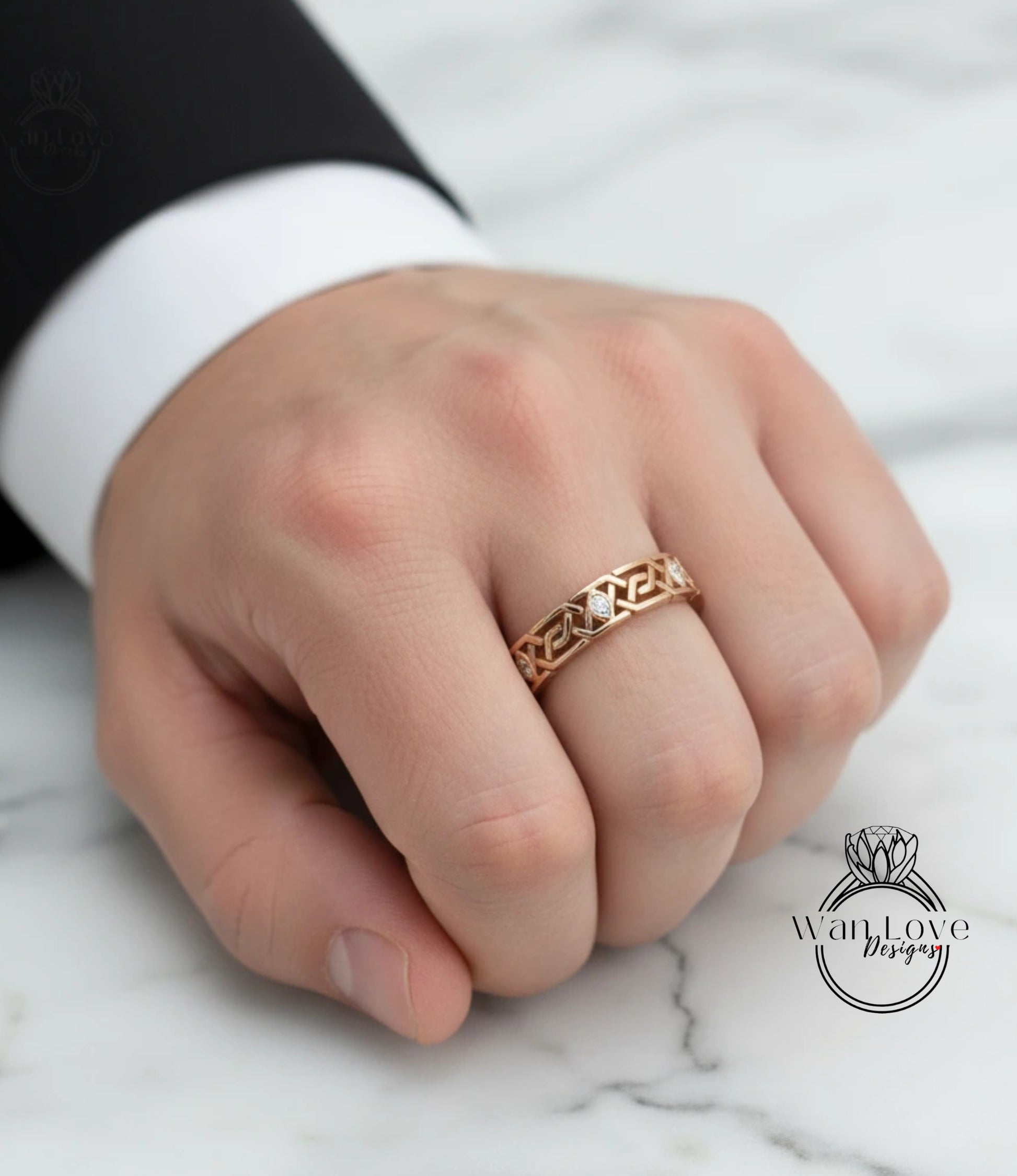 A close-up of a person's hand wearing a gold ring with an intricate design.