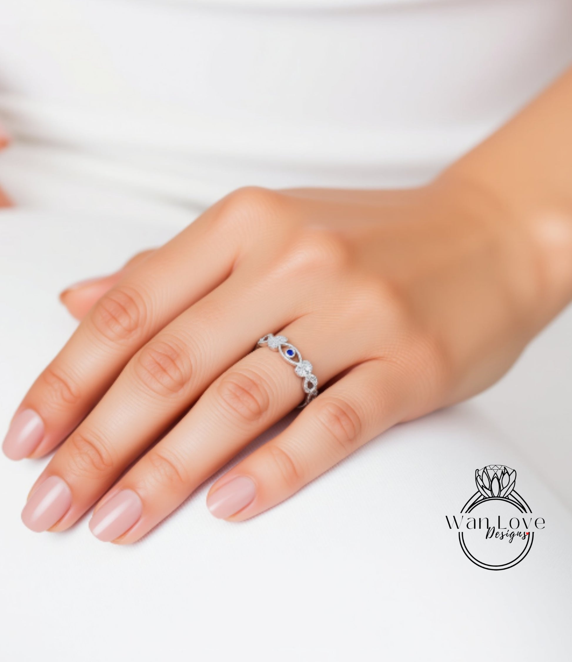A close-up of a hand wearing a silver ring with blue stones.