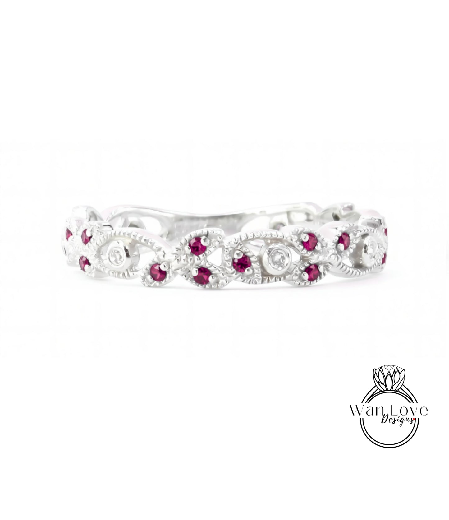 A silver ring with a decorative floral design and red gemstones.