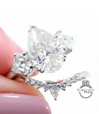 A close-up of a person's hand holding a diamond engagement ring with a large central diamond surrounded by smaller diamonds on either side.